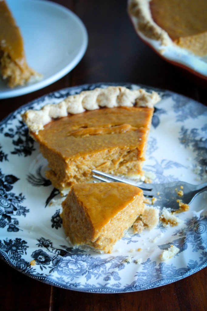 pumpkin pie on plate in front cut